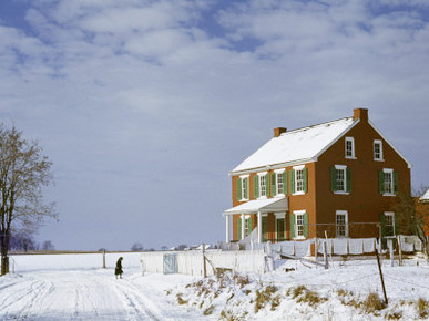 Huddled Figure Walks Up a Snow-Covered Road to an Amish Farmhouse